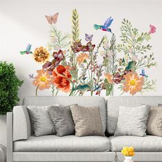 a living room with flowers and butterflies painted on it's wall behind a couch