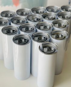 there are many white cans with black lids on the table next to each other and one is empty