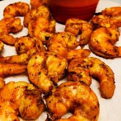 some shrimp on a white plate next to a red bowl