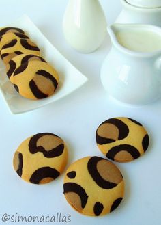 some cookies are sitting on a plate next to milk jugs and a white vase