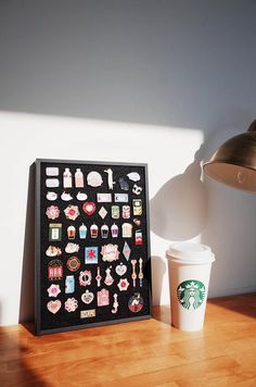 a starbucks cup sitting on top of a wooden table next to a framed sticker