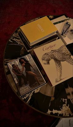 magazines and books on a glass table with red velvet covering the top part of it