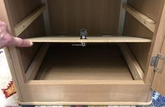 a hand is pointing at the bottom of a cabinet with two shelves on each side