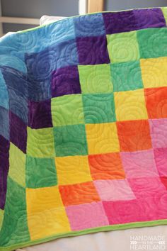 a multicolored quilt sitting on top of a bed