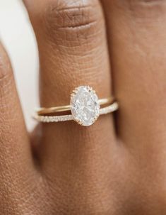 a woman's hand with a diamond ring on top of her finger and an engagement band