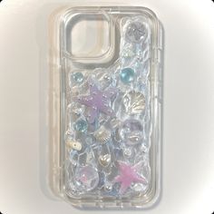 an iphone case with shells and starfishs on the back in clear plastic packaging