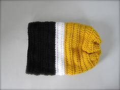 a yellow and black knitted hat laying on top of a white table