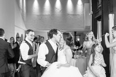 a bride and groom kissing on the dance floor at their wedding reception in black and white