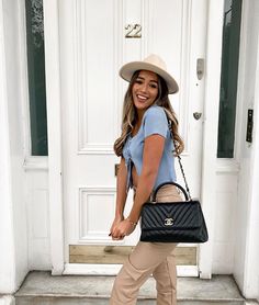 a woman is standing in front of a door with her hand on her hip and smiling at the camera