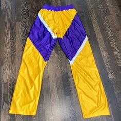 You are bidding on a very cool pair of vintage DeLong basketball warm-up track pants. They are in very nice condition. They are shiny purple with purple, gold, and white They have a thick elastic waistband, are 100% nylon, have zero pockets, and fully unbutton up and down each leg. Size tag reads 36. Total length is 45.5 inches and inseam is 33 inches. The unstretched waist measures 28 inches and can stretch up to 46 inches. The ankle has a couple tiny holes in it and they have one small spot on Retro Stretch Pants For Streetwear, Retro Stretch Sports Bottoms, Retro Stretch Bottoms For Sports, Pep Club, Royal Blue Pants, Sport Trousers, Basketball Pants, Velour Tracksuit, Sports Trousers