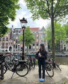 a woman standing next to some bikes on a sidewalk