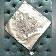 a teal velvet headboard with a white and silver coral design on it, along with a tag