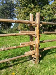 a wooden fence in the middle of a grassy field