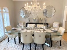 a dining room table with white chairs and chandelier