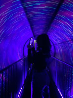 a woman is taking a photo on her cell phone in a tunnel with colorful lights