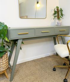 a desk with two drawers and a mirror on the wall above it next to a chair