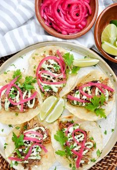 some tacos are sitting on a plate with red onions and cilantros