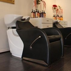 two black and white chairs sitting next to each other in front of a wall with bottles on it