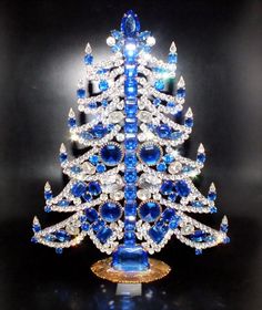 a blue and white christmas tree made out of crystal stones on a gold plated stand