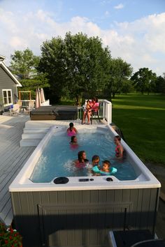 a group of children in a hot tub on a deck with an adult and two adults