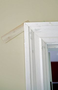 the corner of a room with a white door and a piece of wood sticking out of it