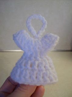 a crocheted angel ornament being held up by someone's hand