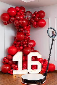 a balloon arch with the number sixteen displayed in front of it and red balloons behind it