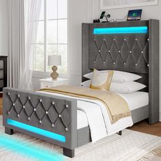 a bed that has some lights on the headboard and foot board in front of it