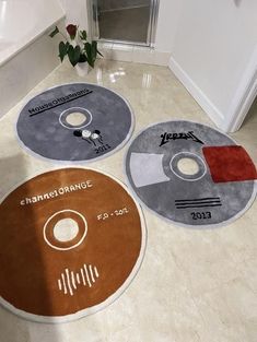 three circular rugs with various logos on them in a bathroom area next to a toilet