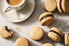 there are many macaroons next to a cup of coffee