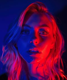 a woman with red and blue light on her face, looking at the camera while she is