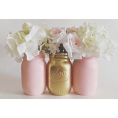 three pink mason jars with white flowers in them