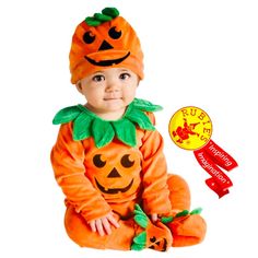 a baby in a pumpkin costume sitting on the ground