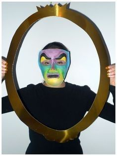 a man with his face painted in different colors is holding up a circular frame that has an image of a person's face on it