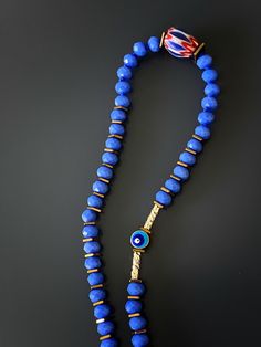 The Yoga Meditation Necklace is stylish and symbolic. Featuring blue crystal beads with an Om mantra, evil eye, lucky elephant and meditation pendant this necklace is guaranteed to invite good energy. The Om mantra is a sacred mantra known as the sound of the universe. The vibrations of the Om sound is said to energize all chakras and help one connect with their Divine Self. Om is said to be a direct expression of God, so it makes prayers more effective by increasing pranic energy. The Evil Eye Blue Spiritual Necklaces With Large Beads, Spiritual Blue Necklaces With Large Beads, Blue Large Beads Spiritual Jewelry, Blue Evil Eye Jewelry For Meditation, Spiritual Blue Jewelry With Large Beads, Blue Amulet Beads For Gifts, Blue Amulet Beads For Gift, Handmade Blue Jewelry For Blessing, Blue Spiritual Beads With Colorful Details