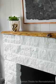 a white fireplace with a potted plant on the mantle and a painting above it