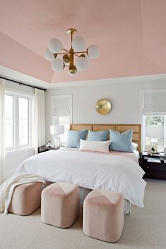 a bedroom with pink walls and white bedding, two foot stools on the floor