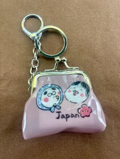 a pink purse keychain with two cats on it and the word japan written in japanese