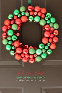 a christmas ornament wreath hanging on the front door with green and red ornaments