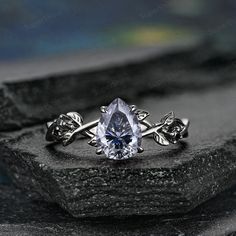 a white gold ring with an oval blue topazte surrounded by leaves and vines