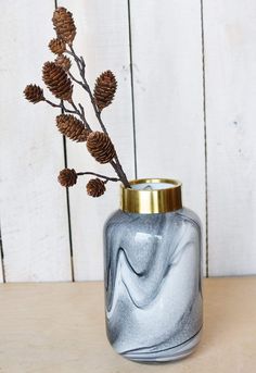 a glass vase with some pine cones in it