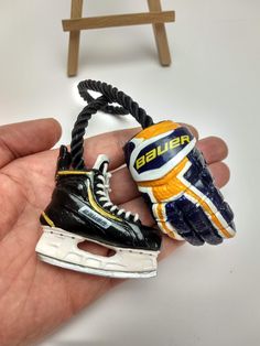 a hand holding an ice hockey shoe and helmet ornament