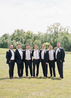 a group of men standing next to each other on top of a lush green field