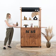 a woman standing in front of a wooden counter with bottles on it and a sign that says n'65