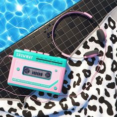 a pink and green radio sitting on top of a blanket next to a swimming pool