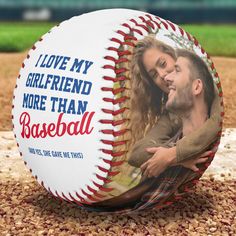 a baseball with a photo of a man and woman on the front is sitting in dirt