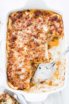 a casserole dish with meat, cheese and sauce in it on a white surface