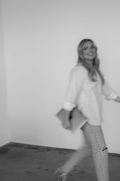 black and white photograph of a woman walking in an empty room with her hand on her hip