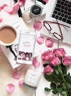 pink roses, candles, eyeglasses and cell phone on a white table with rose petals