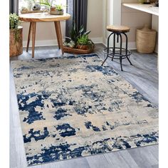 an area rug with blue and beige colors on the floor in front of a window